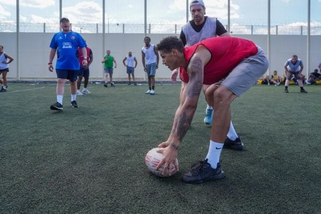 An outdoor rugby training session, featuring a focused player placing a rugby ball on the ground