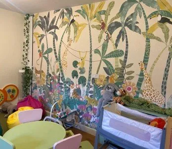 Playroom at our refuge with jungle theme wall paper, soft toys and furnishings and a kids table and chairs.
