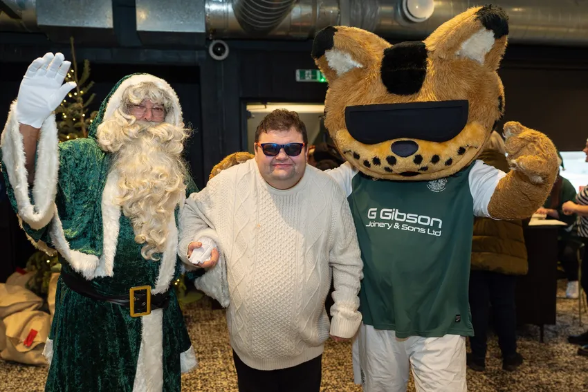 Community member with Hibs Santa and Sunshine mascot at Christmas Meal at Easter Road Stadium