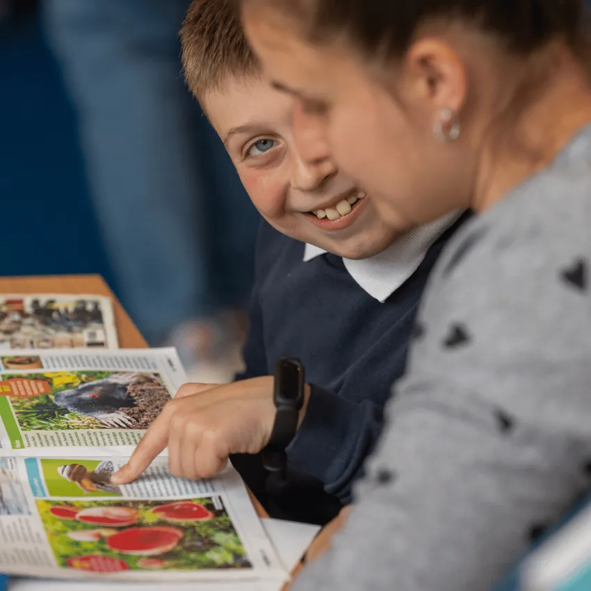 Child enjoying reading a magazine with his mother at a Learn to Love to Read event