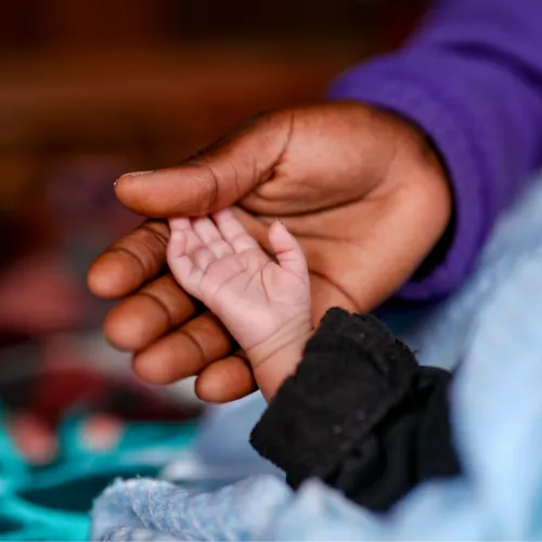 Baby's hand rests against mother's hand