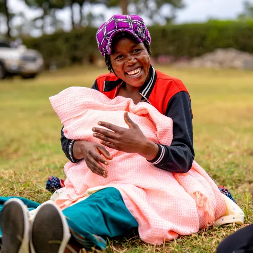 Woman holds her baby, who is wrapped up in a blanket