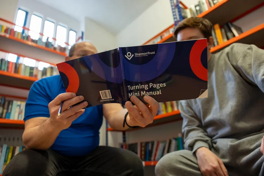 Two men in prison reading a Turning Pages manual