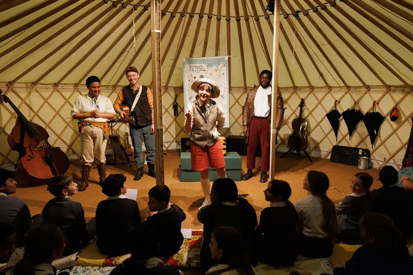 Four actors perform a show about local history inside the yurt, children sat on floor watching