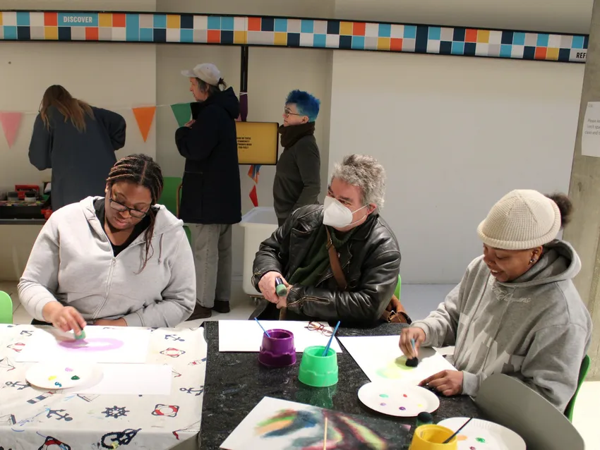 Three members making art work around a table