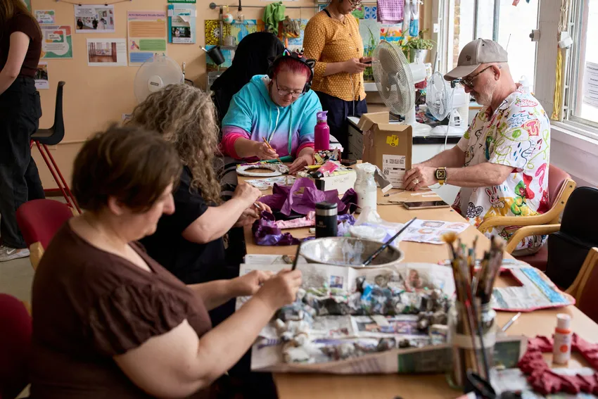 Several people around a table making sculptures in studio sessions