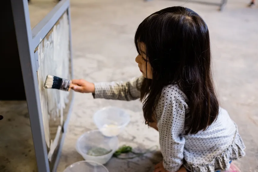 A child painting clay slip on a glass surface.