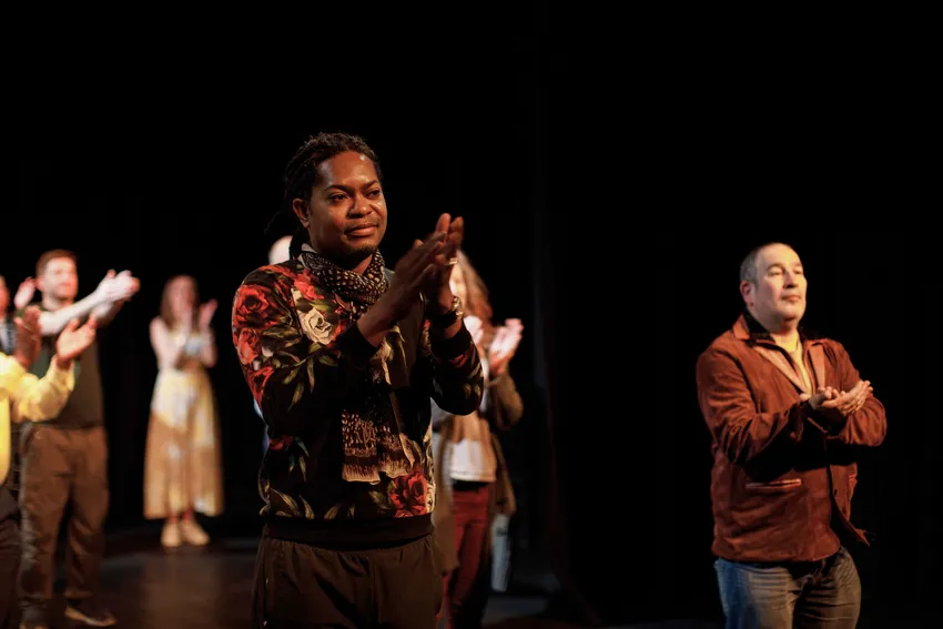 Participants from OETC intermediate acting skills group clapping at an audience during a curtain call