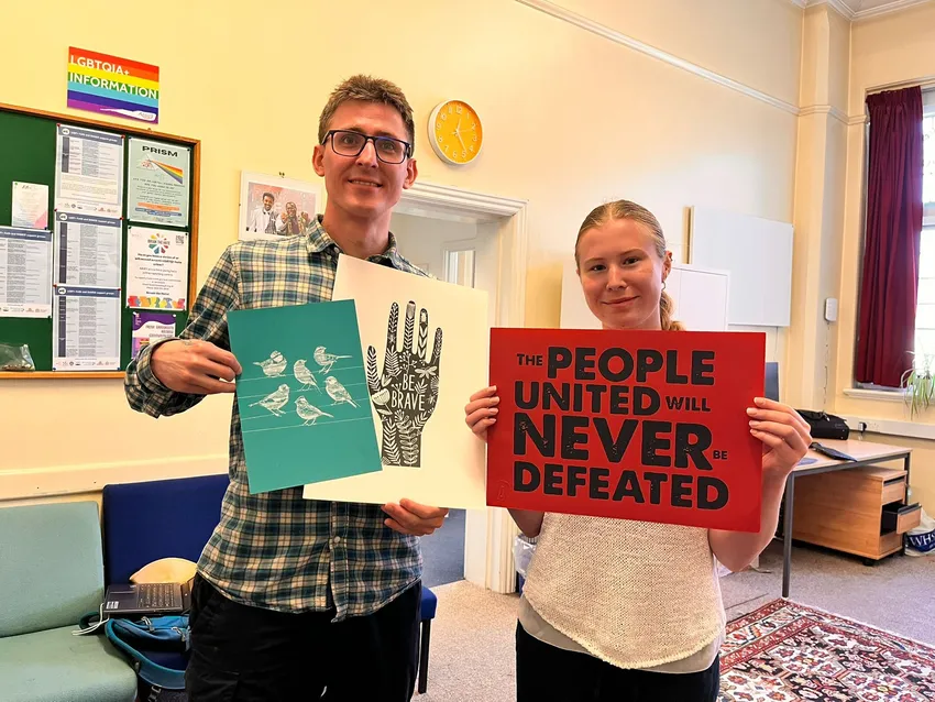 Volunteers holding signs of solidarity. The people united will never be defeated.