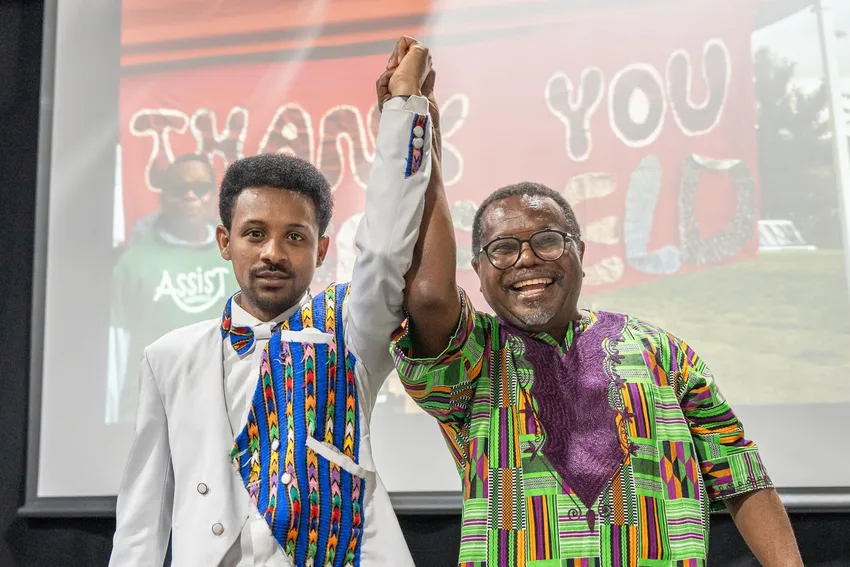 Two ASSIST community members celebrate our work on stage at our 20th anniversary celebration