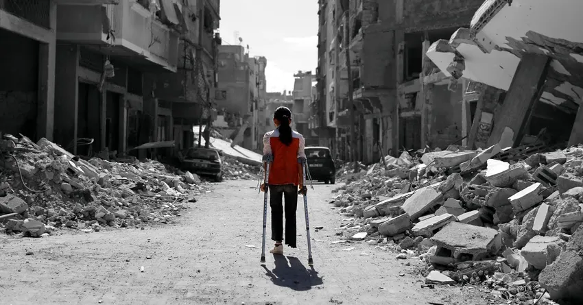 A child with limb loss in Gaza walks in the rubble using crutches