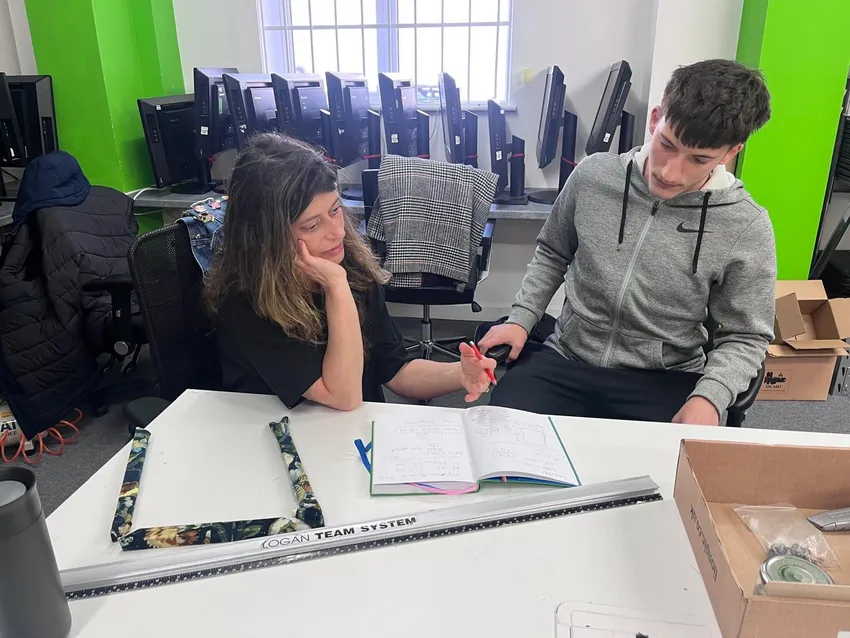 Debs and her trainee sit at a desk designing a new picture frame