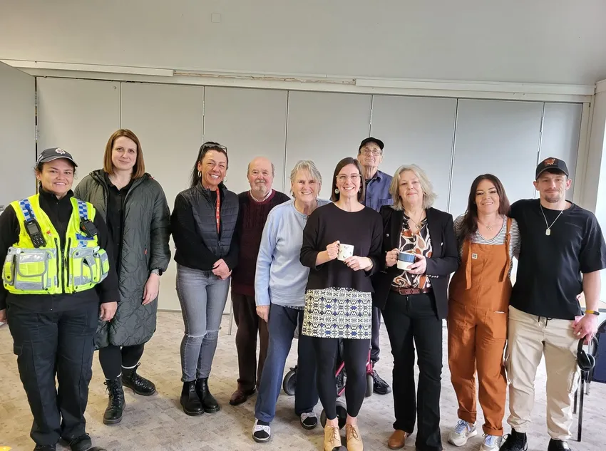 People at Linden Breakfast Club, including PCSO and Council staff, with a mug, smiling together