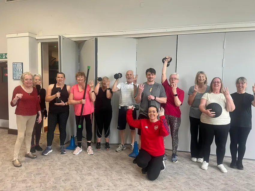 A group of people with gym equipment smiling together